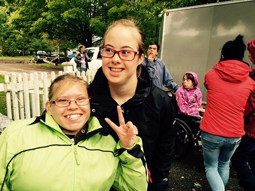 Deux participantes souriantes, l'une faisant un signe de paix, lors d'un événement communautaire en plein air