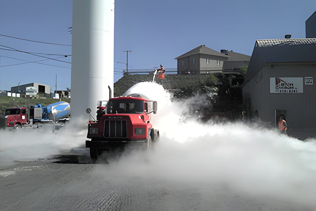 Un ouvrier arrose d'azote liquide une benne de béton fumante sur un chantier