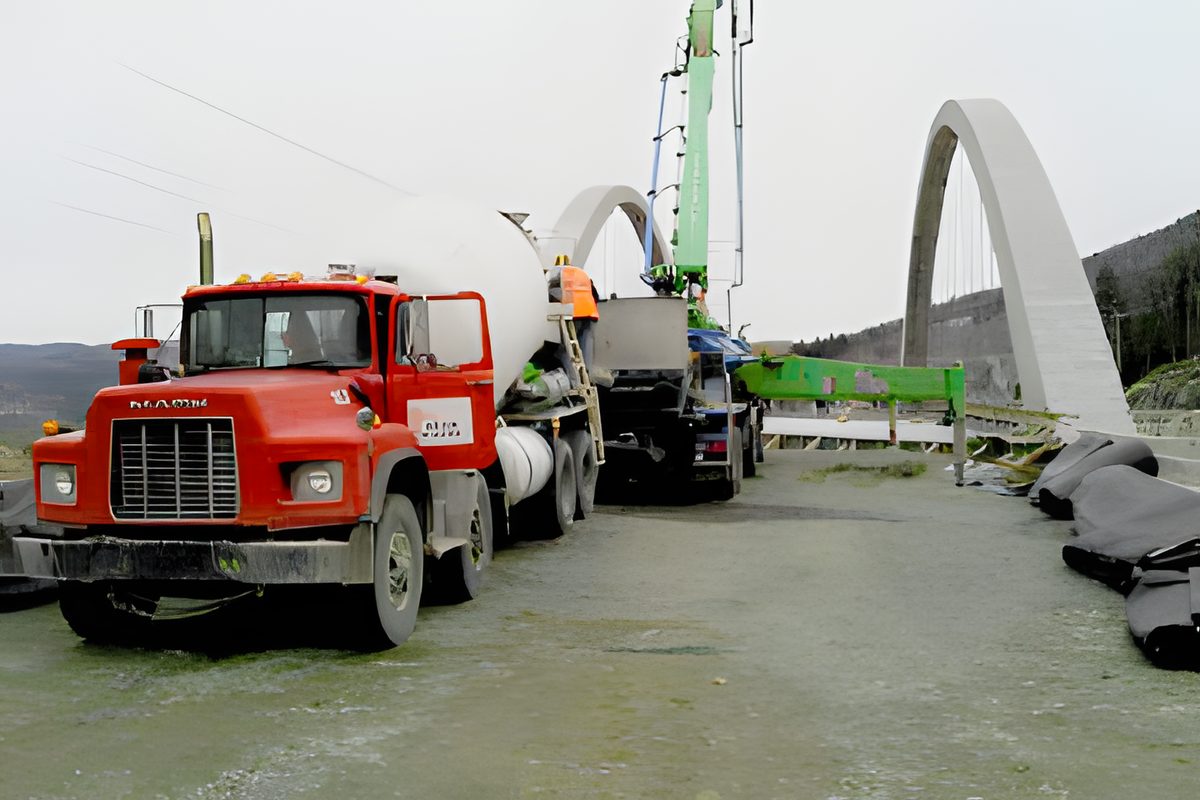 La coulée du pont en arche : le tablier en construction, les coffrages et la grue au-dessus de la rivière