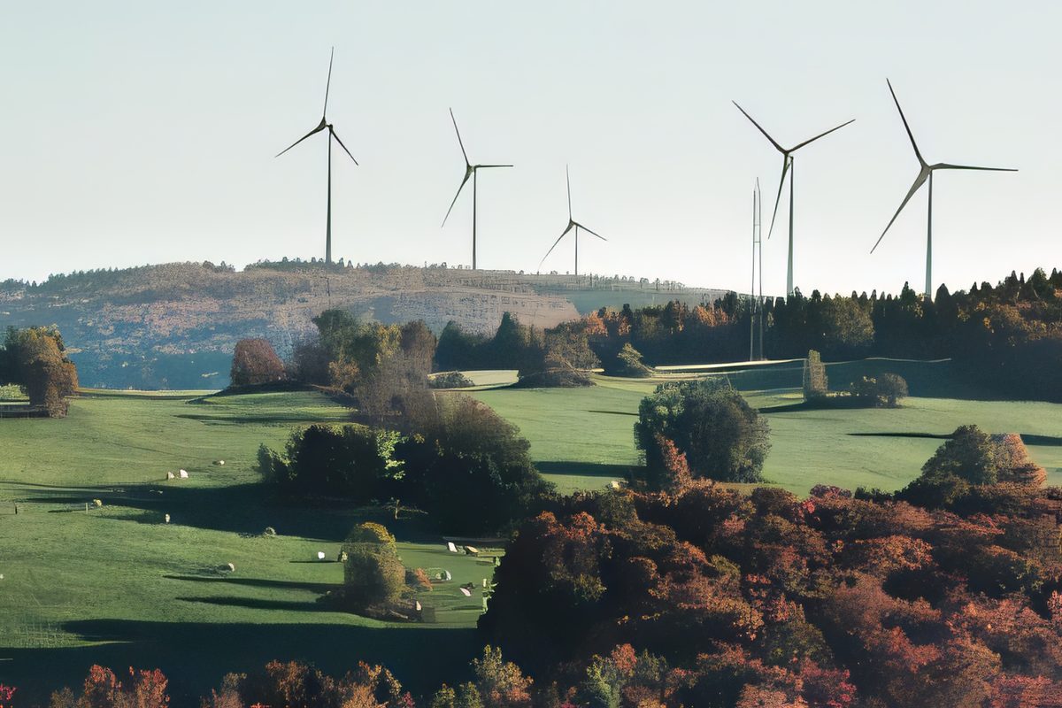 Six éoliennes au-dessus des champs et des érables rouges, des vaches au pâturage devant
